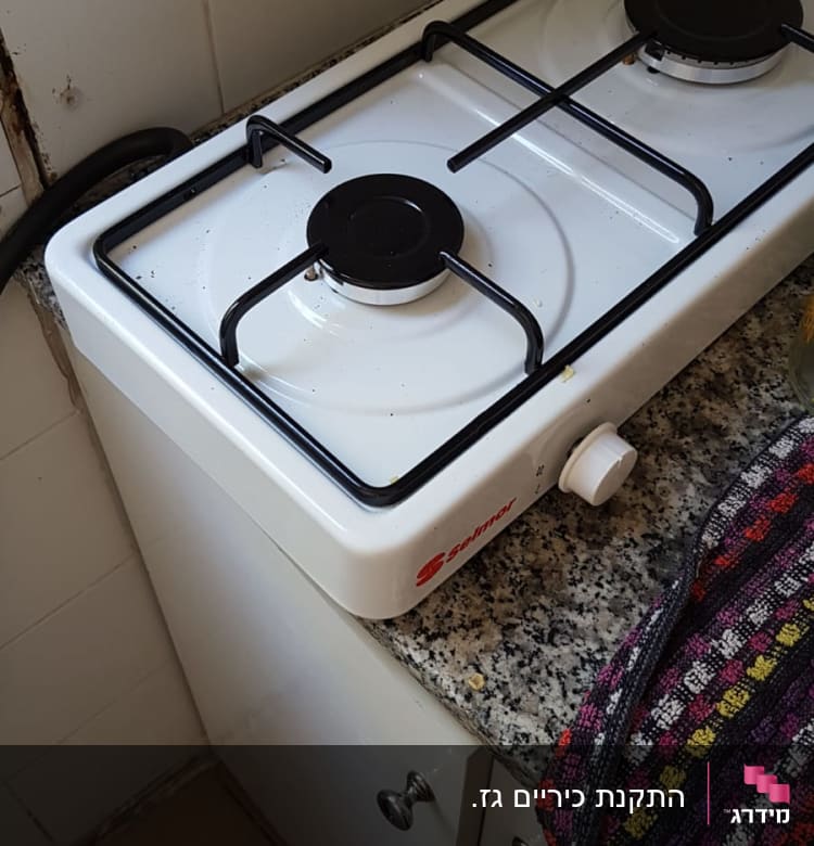 כיריים גז לבנים עם שני מבערים על משטח גרניט